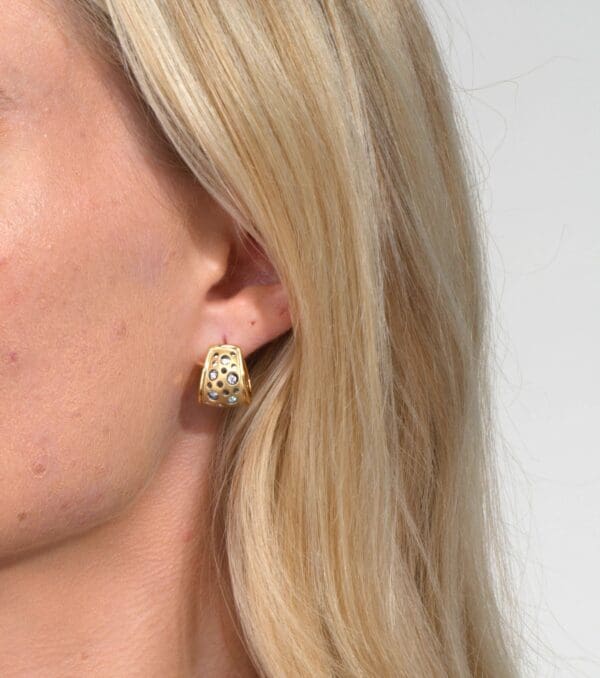 A woman wearing gold earrings with white background