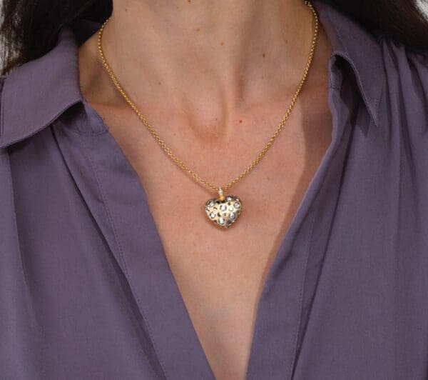 A woman wearing a purple shirt and gold necklace.