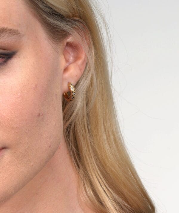 A woman with long blonde hair wearing gold earrings.