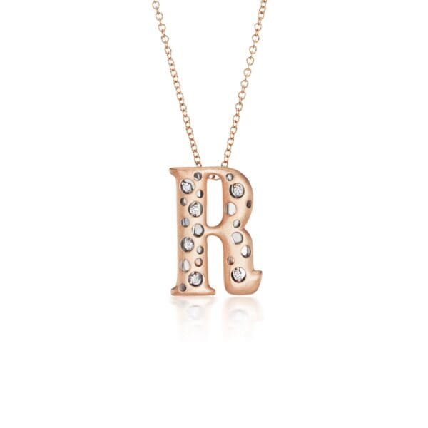 A rose gold necklace with the letter r