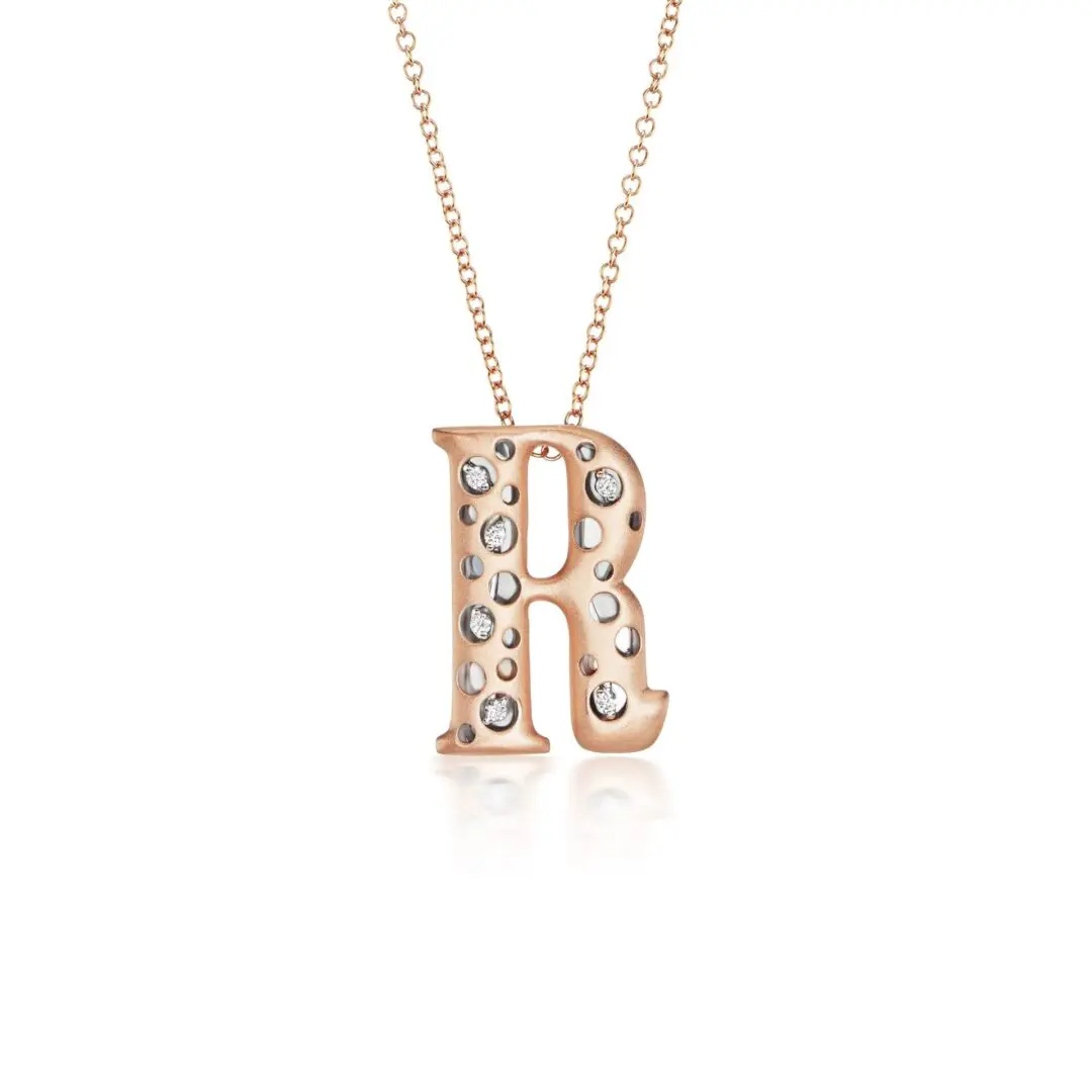 A rose gold necklace with the letter r