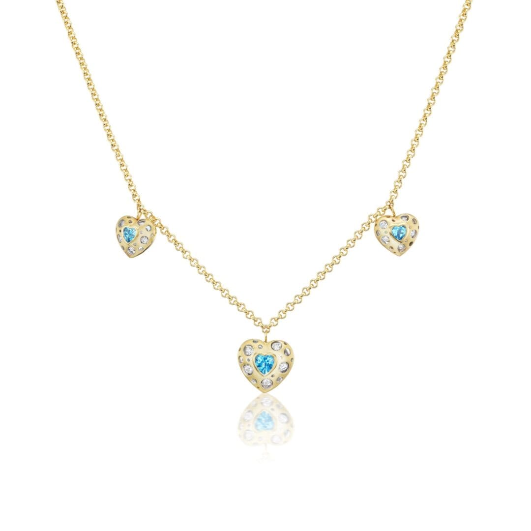A gold necklace with three blue hearts on it.
