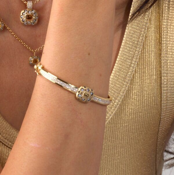A woman wearing a gold bracelet and necklace.