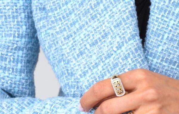 A woman wearing a blue sweater and holding her hand on the ring.