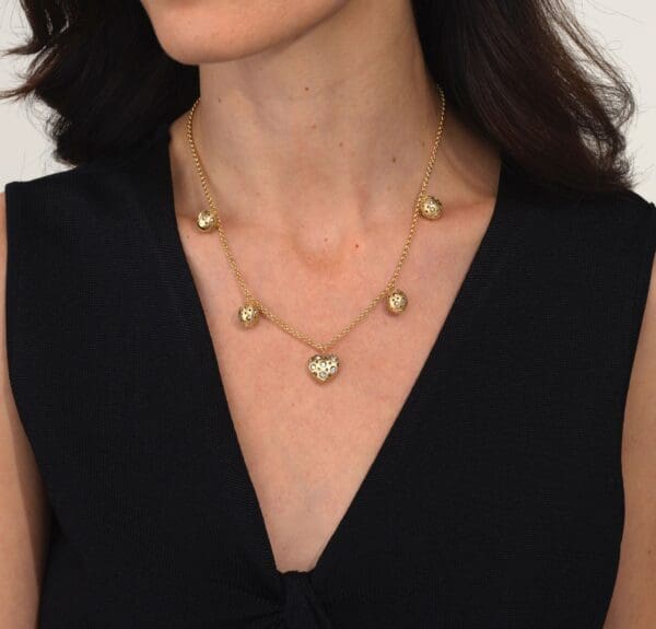 A woman wearing a black top and gold necklace.