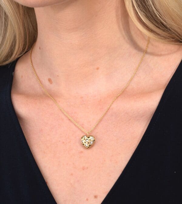 A woman wearing a necklace with a heart shaped pendant.