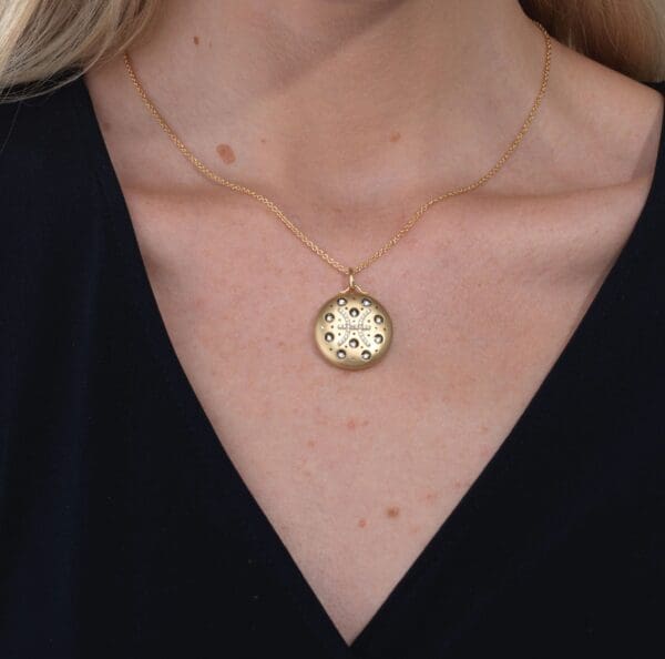 A woman wearing a necklace with a gold pendant.