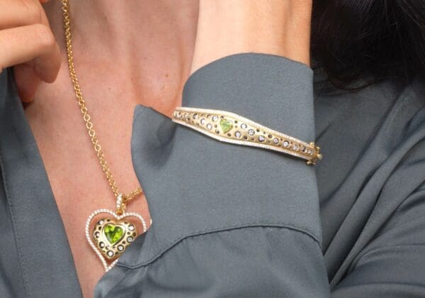 A woman wearing a necklace and bracelet with a heart shaped pendant.