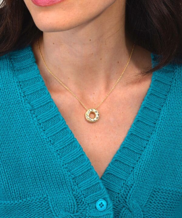 A woman wearing a sweater and holding onto a necklace
