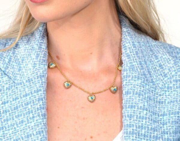 A woman wearing a necklace with five small hearts.