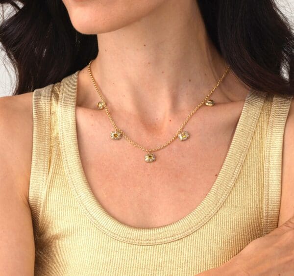 A woman wearing a gold necklace with small round beads.