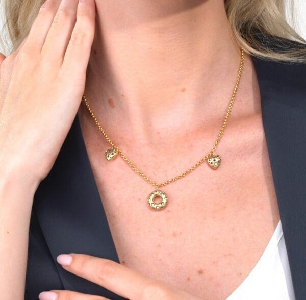 A woman wearing a necklace with three charms.