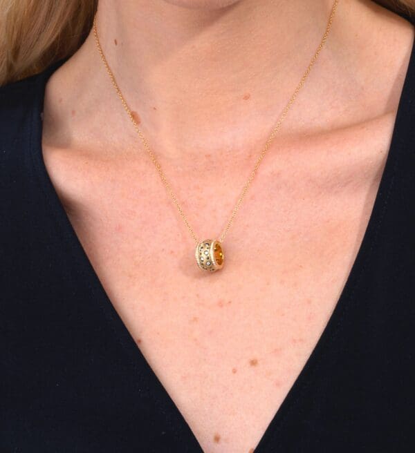 A woman wearing a necklace with two different colored rings.